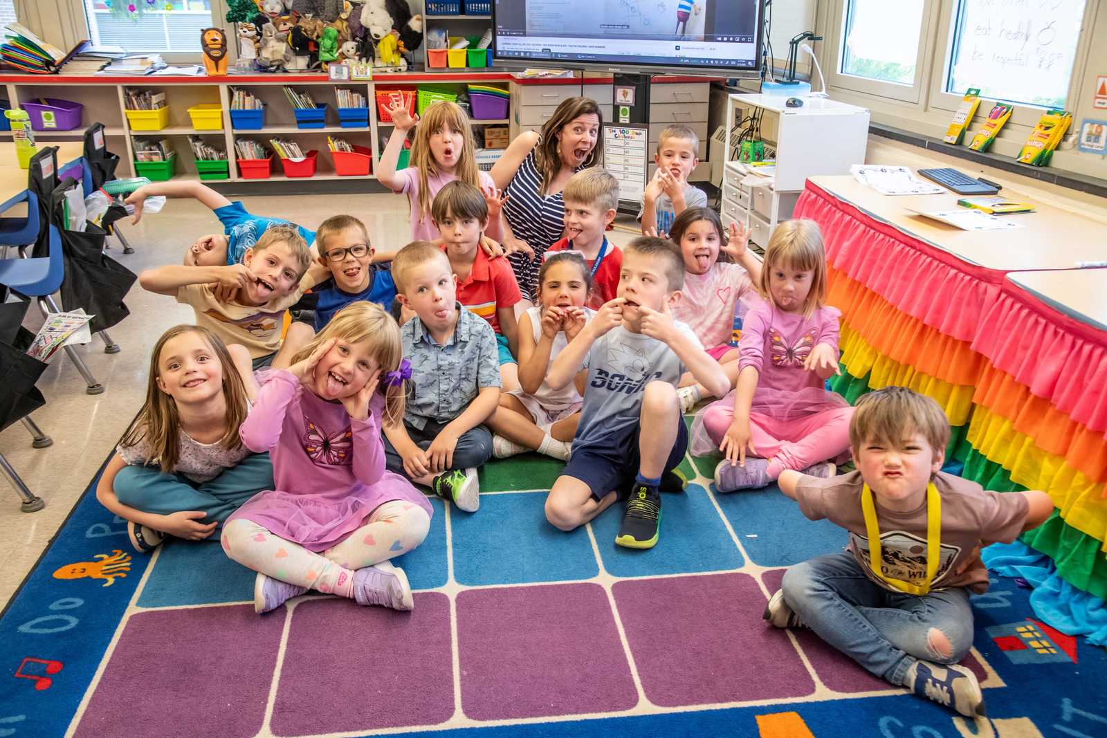 A Lower Elementary class making silly faces with their teacher