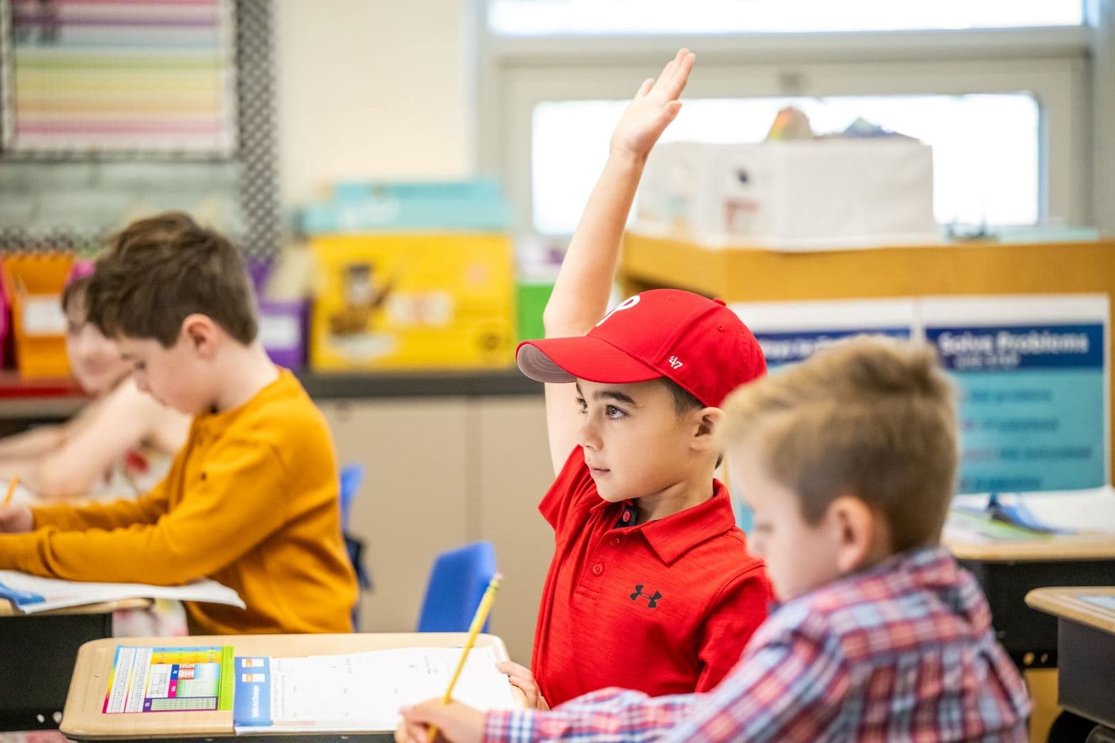Student raising a hand in a Lower Elementary classroom
